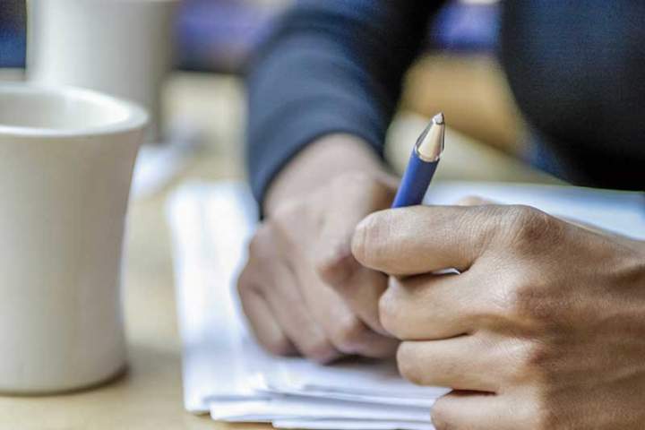 Bild på händer som håller penna och papper på skrivbord